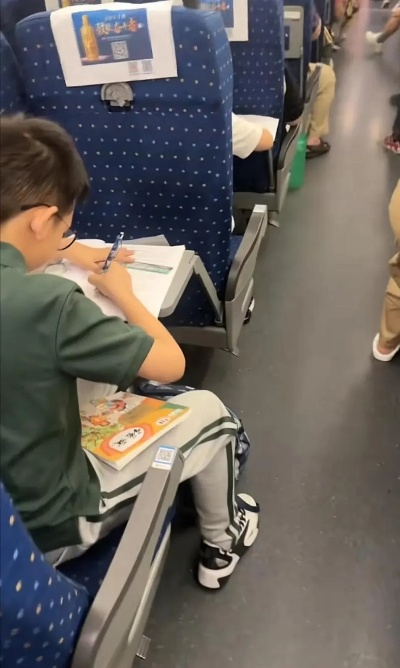 高铁车厢里的晚自习，孩子们在旅途中赶作业的背影